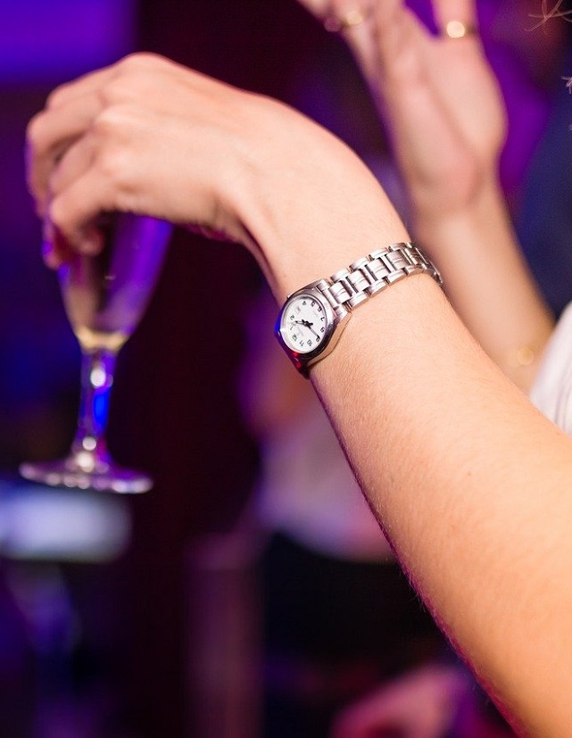 Close up shot on a woman's hands, holding a glass of alcohol at a night club