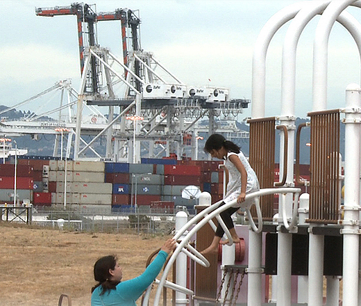 woman and child at playground in front of freights