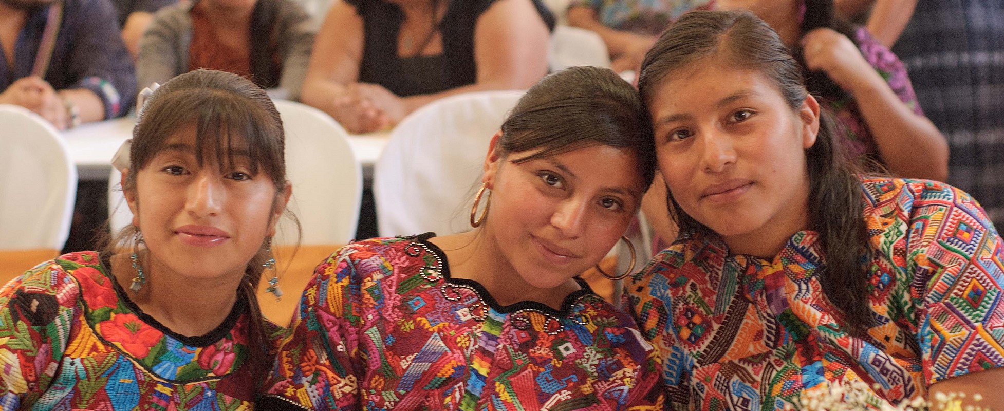 three young women sitting, wearing colorful clothing