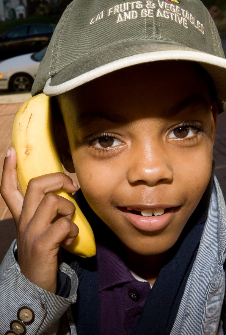 young boy using banana as a telephone