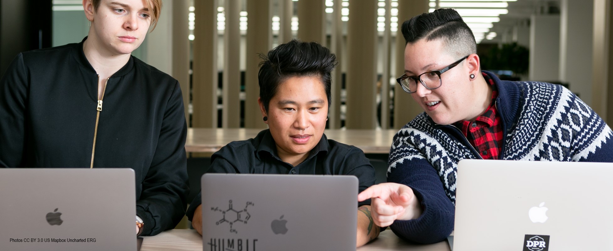 three people on laptops in office setting