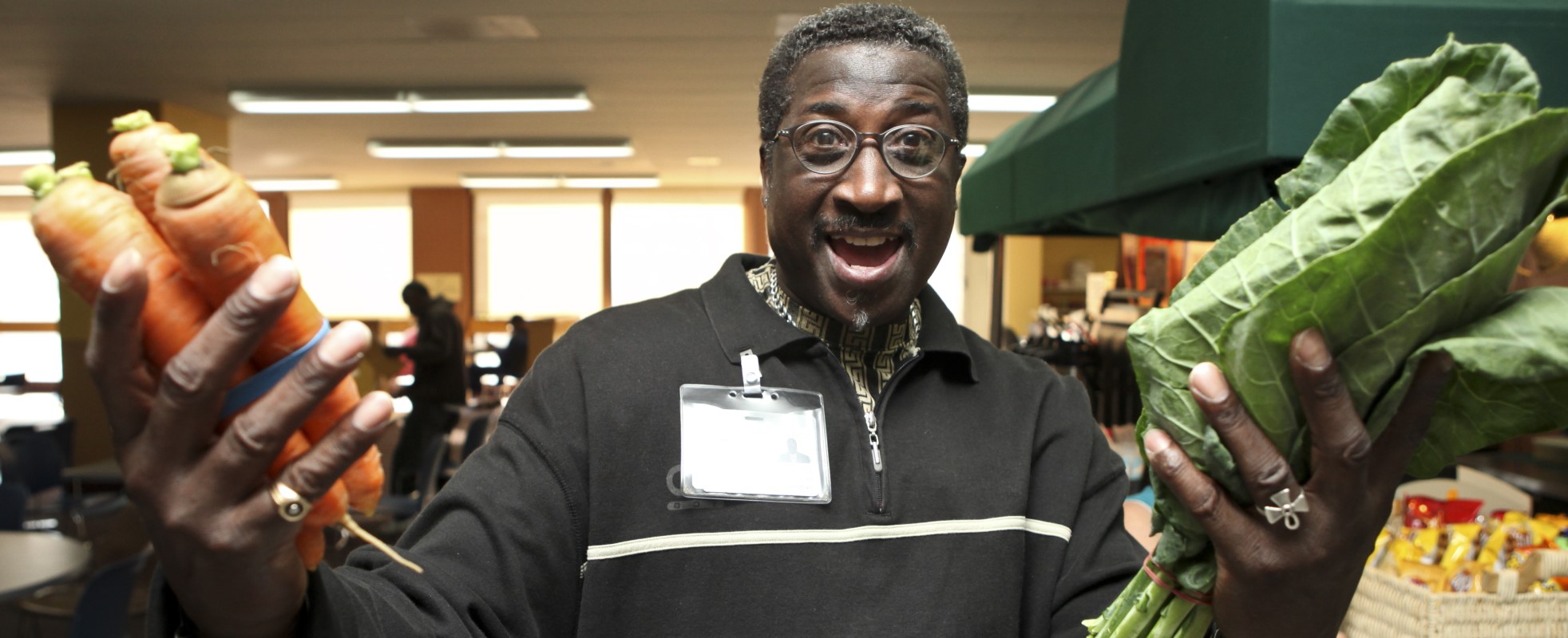 hospital employee holding carrots in one hand and lettuce in the other hand