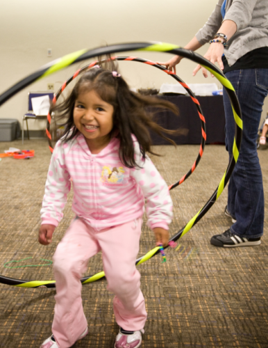 Girl playing with hula hoops in a classroom