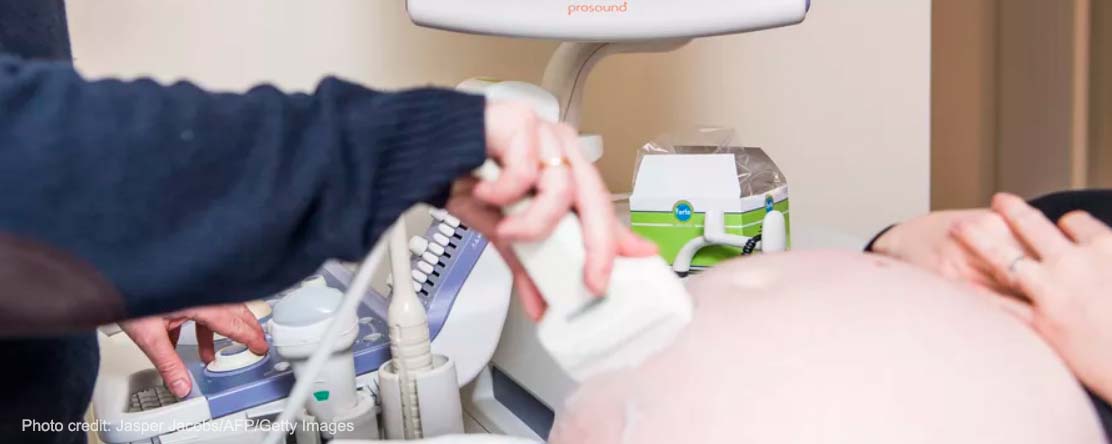 A doctor performs an ultrasound examination on a pregnant woman