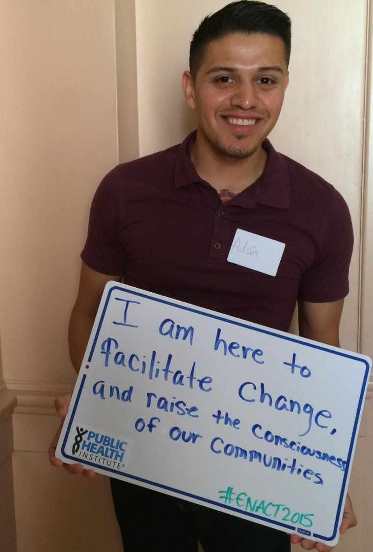 man holding sign that says "I am here to facilitate change and raise the consciousness of our community"