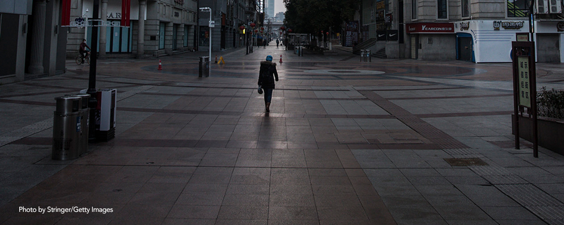 A resident wears a protective mask as she walk on an empty business street on February 13, 2020, in Wuhan, Hubei province, China.