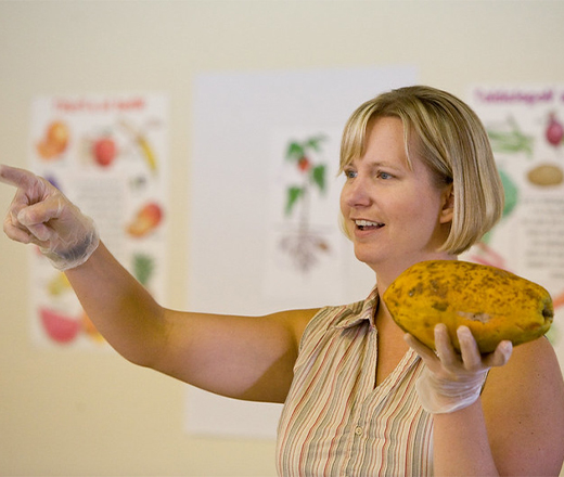 woman holding fruit in front of class