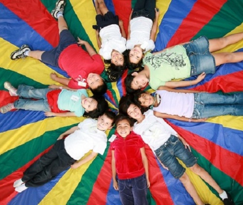 Children on a parachute, looking up and smiling