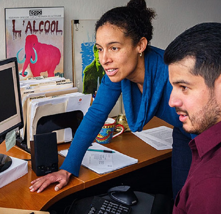 Two people looking at a computer with a dataset on it