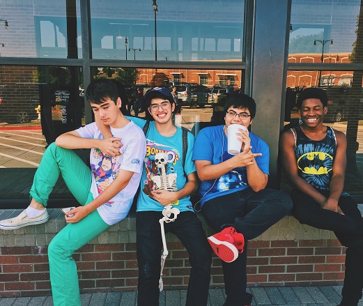 four teen boys sitting on a brick wall in summer. Photo by kat wilcox from Pexels