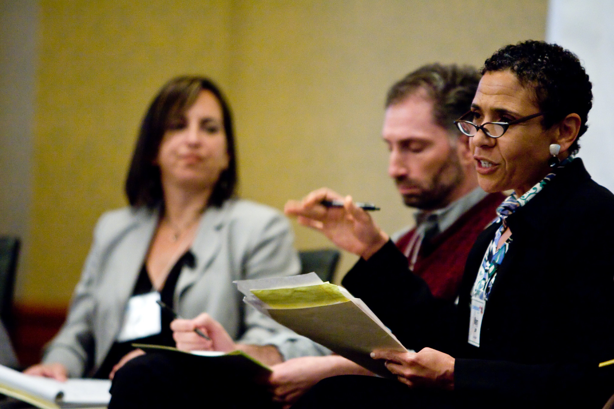 woman with stack of papers in hand, speaking to unseen person