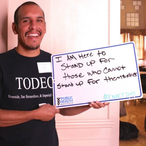 young man holding a white board, on which is written, I am here to stand up for those who can't stand up for themselves.