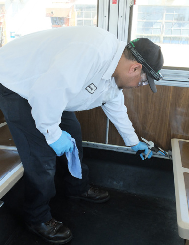 A worker spraying a bus with pesticides, following proper safety protocol