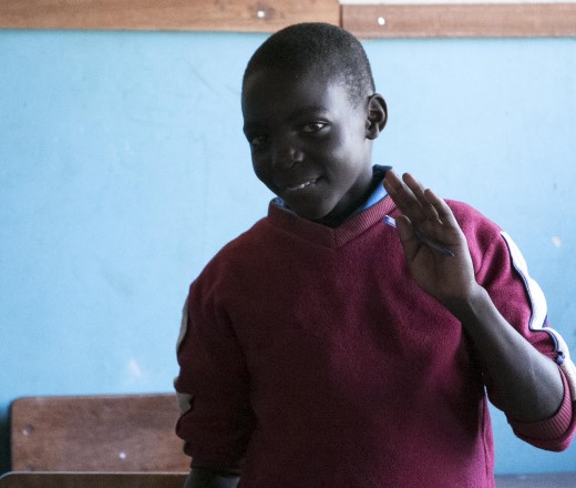 boy shyly waving at camera