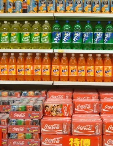 Cans and bottles of soda, stacked at a store