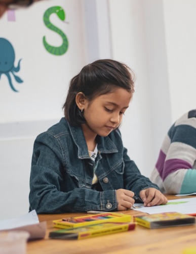 Girl in school, writing at a desk. Photo by Pragyan Bezbaruah from Pexels