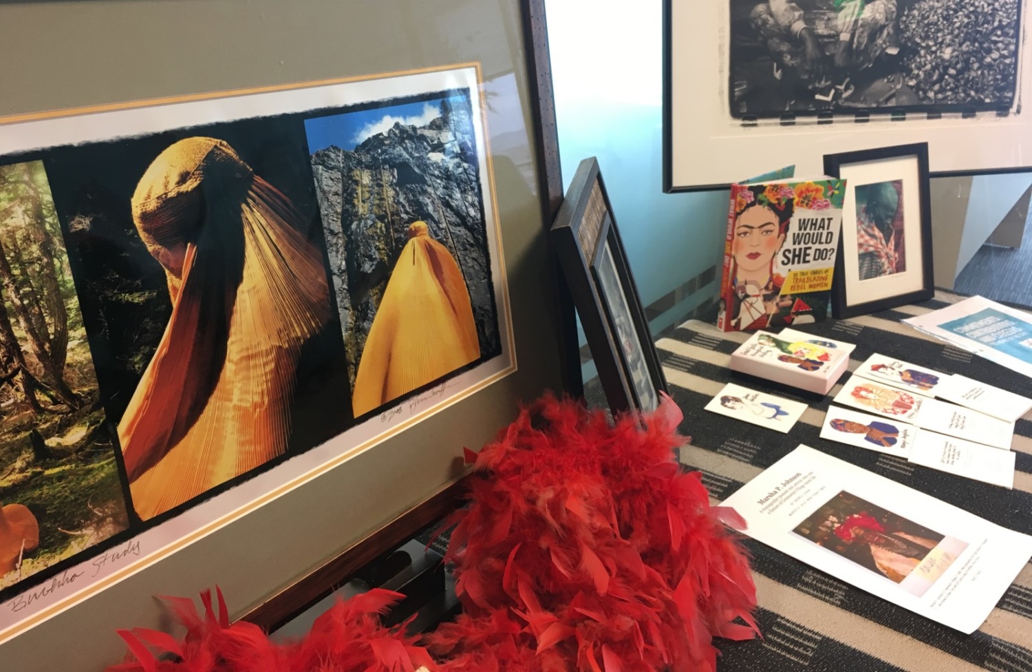 a table with books, a painting, a red feather boa