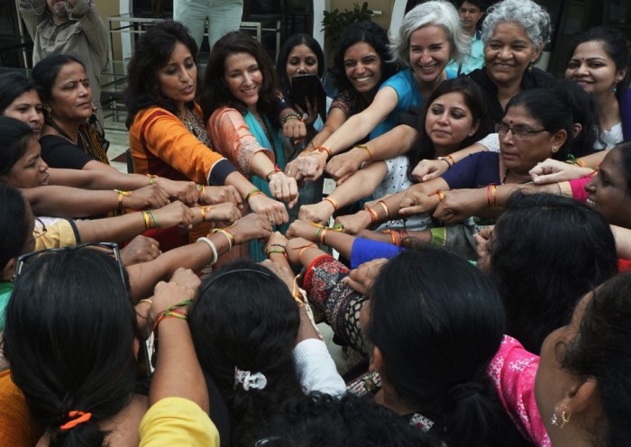 women touching hands victoriously in center of a circle