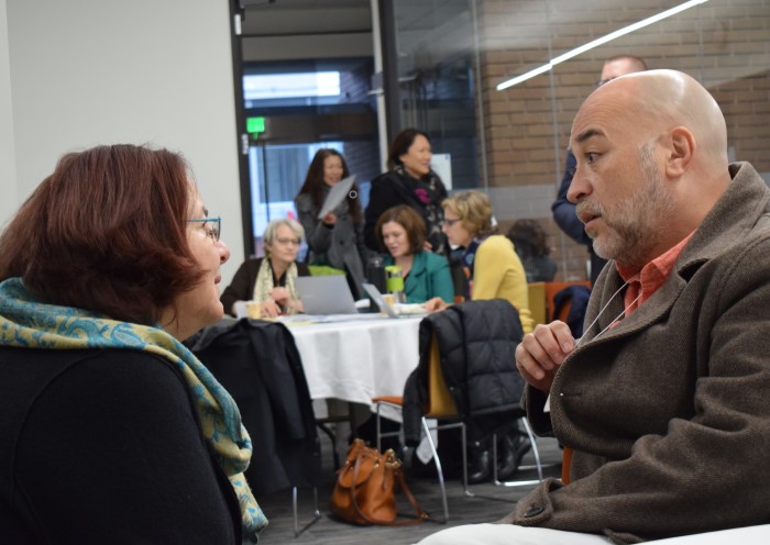 A man and a woman, both Latinx, profiled facing towards each other, intently engaged