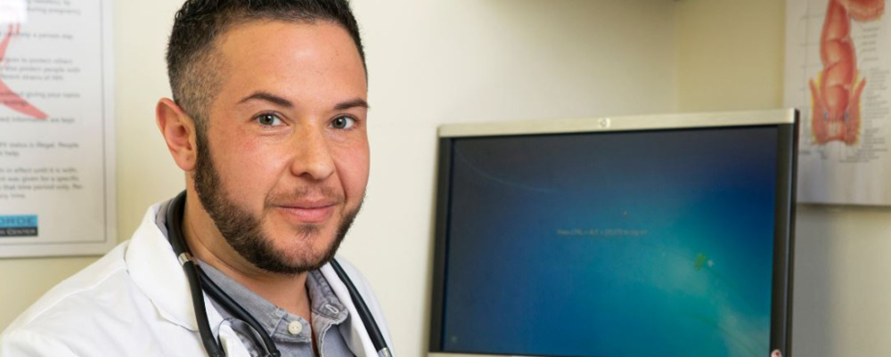 A transmasculine doctor at his computer.