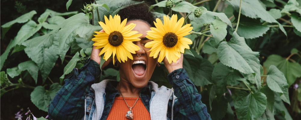 a young woman holding sunflowers in front of her eyes