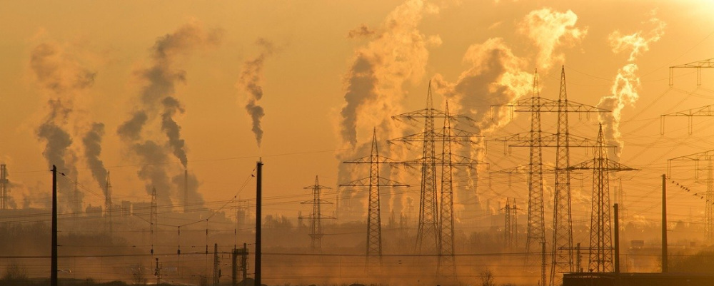 smoke pouring from smokestacks in a hazy field