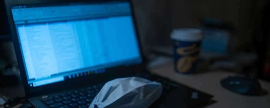 a blue laptop screen with a white mask on the keyboard