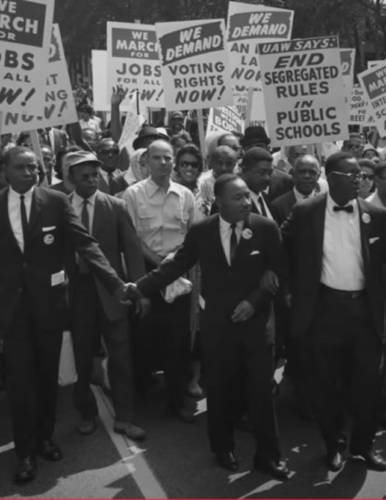 a black and white photo of a civil rights march led by Martin Luther King Jr with people holding "end school segregation" signs