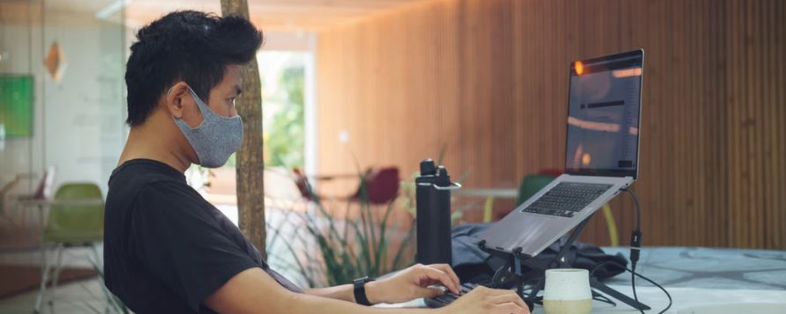 a contact tracer in a mask working on a laptop