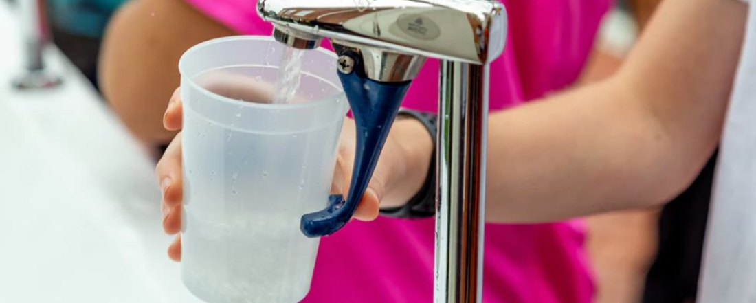 holding a plastic cup under a water dispenser