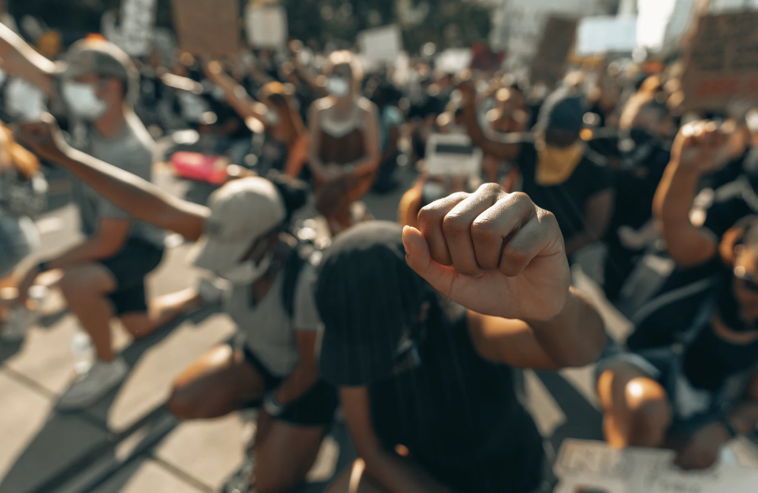 black lives matter demonstration with participants kneeling with their fists in the air