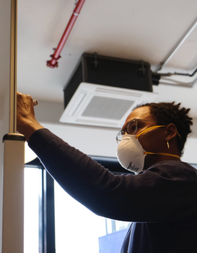 a man in a mask writing on a board at the front of a room