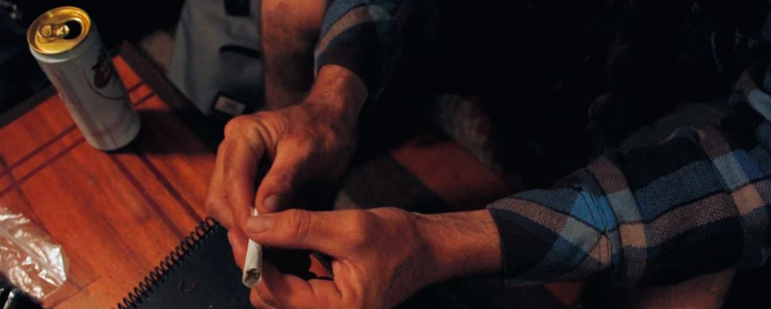 a man's hands holding a marijuana joint
