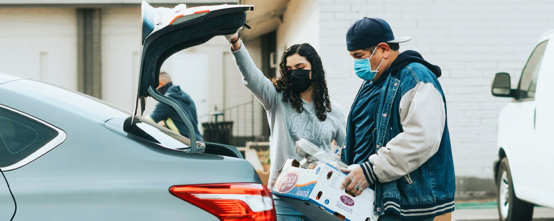 a man and women loading groceries in the trunk of their car