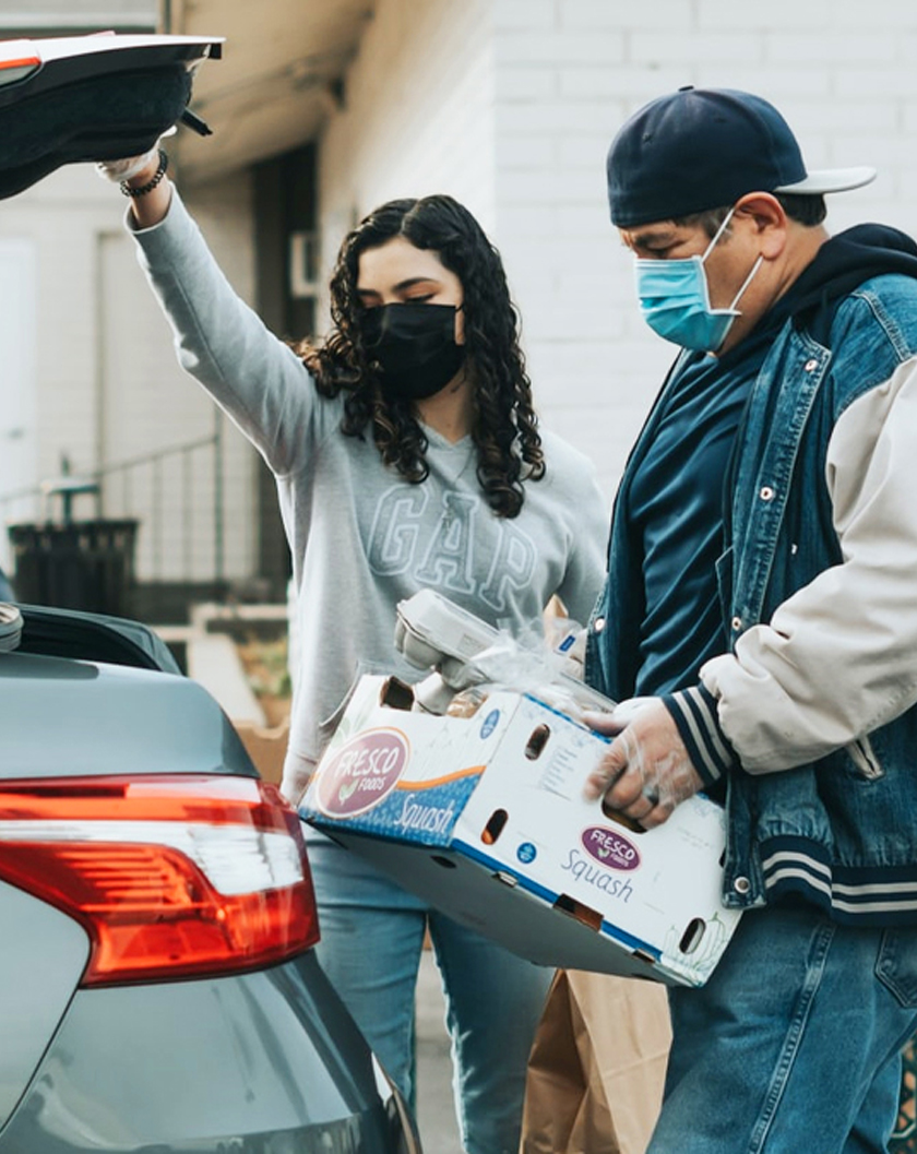 a man and women loading groceries in the trunk of their car