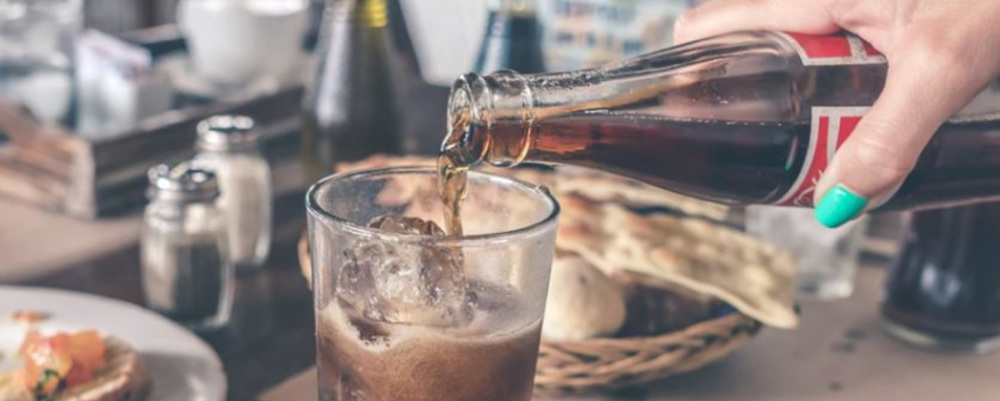 pouring a soda into a glass of ice