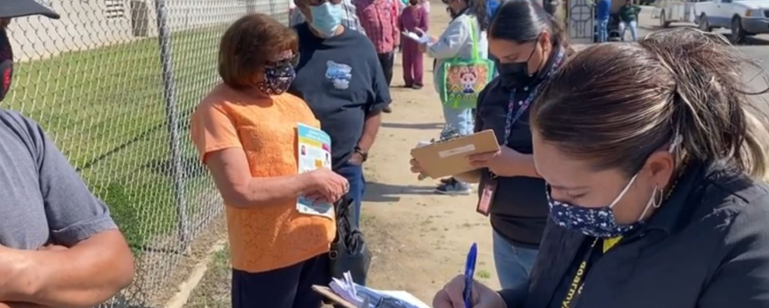 people in line for vaccinations while staff help them fill out forms