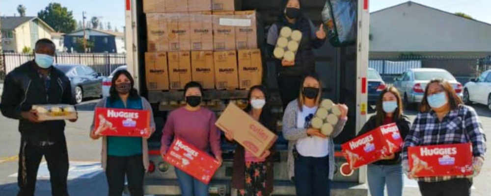 Volunteers holding give-away items in front of a truck