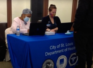 two women behind desk at vaccination site