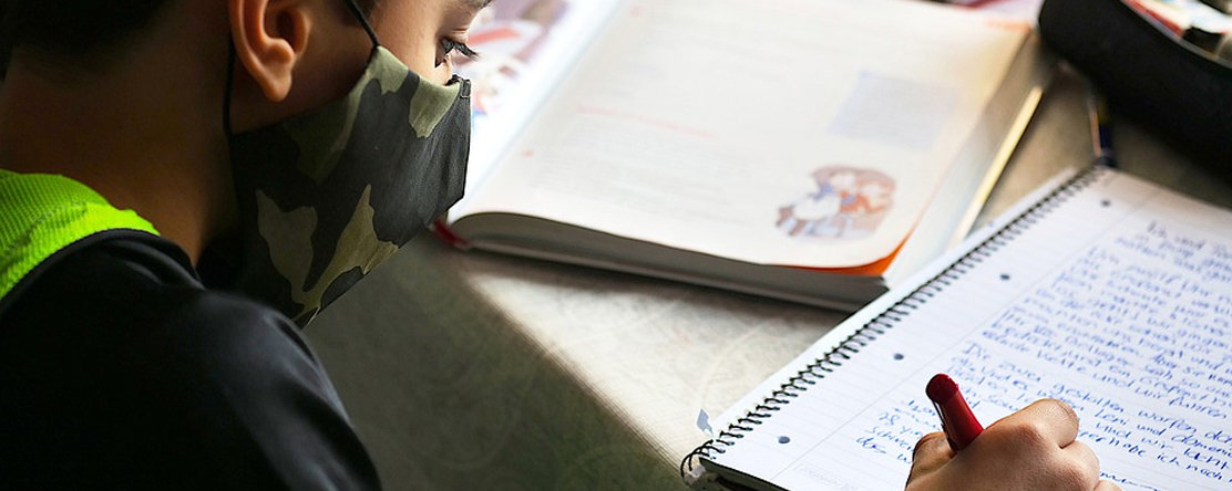 child wearing mask studying