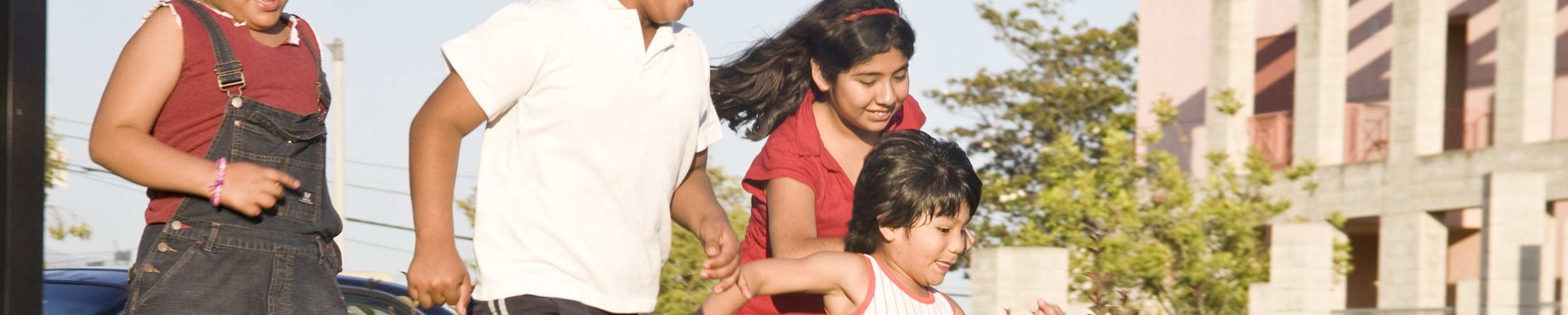 Kids running in a field with buildings in the background