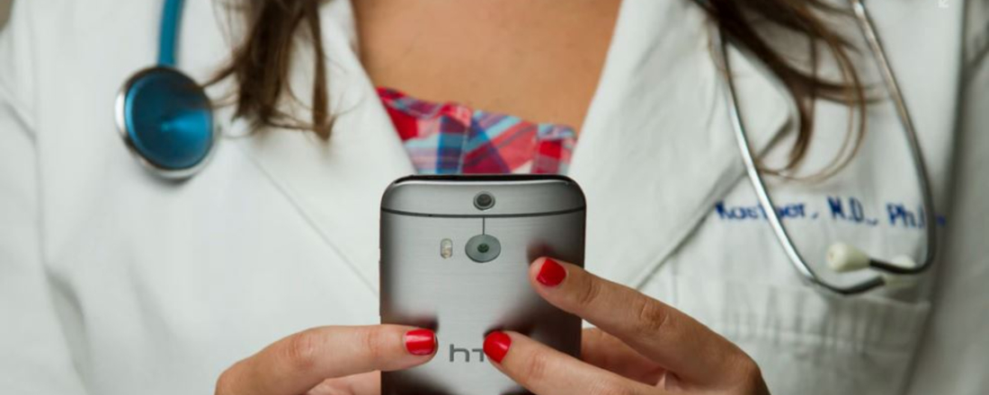 a doctor in a white lab coat holding a cell phone