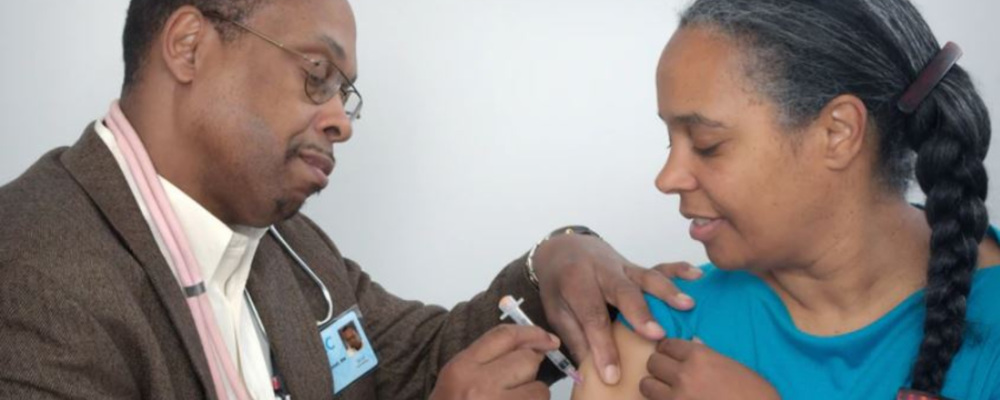 a medical provider giving a vaccination shot to an African American woman