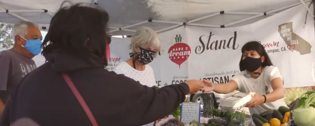 farmers market staff handing a flyer to a customer