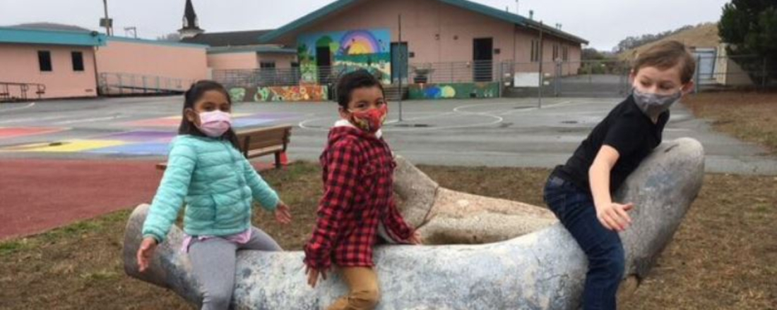 Three children playing on a school play structure