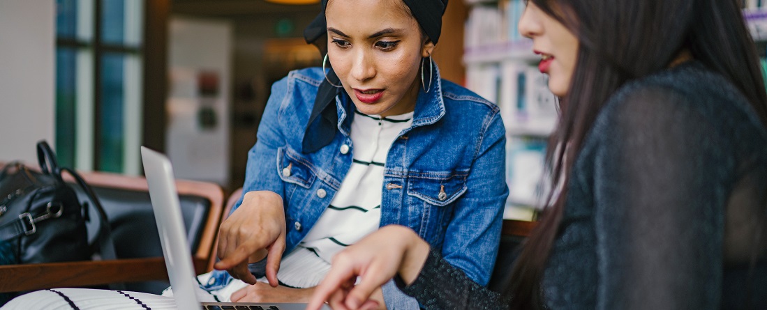 Two women looking and pointing at a laptop