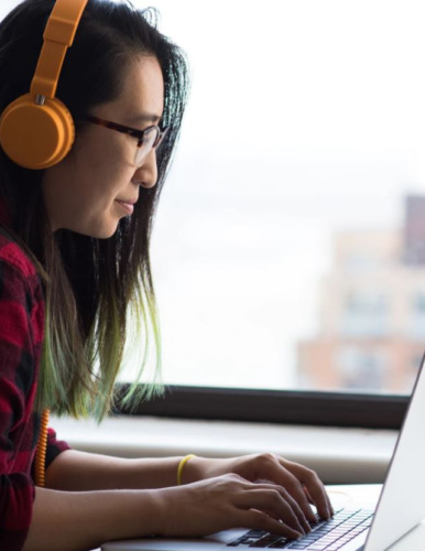 a woman with headphones typing on a laptop