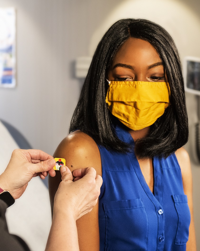 Woman wearing a face mask and receiving a vaccine in a doctor's office