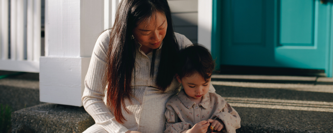 a pregnant women sitting outside with her child