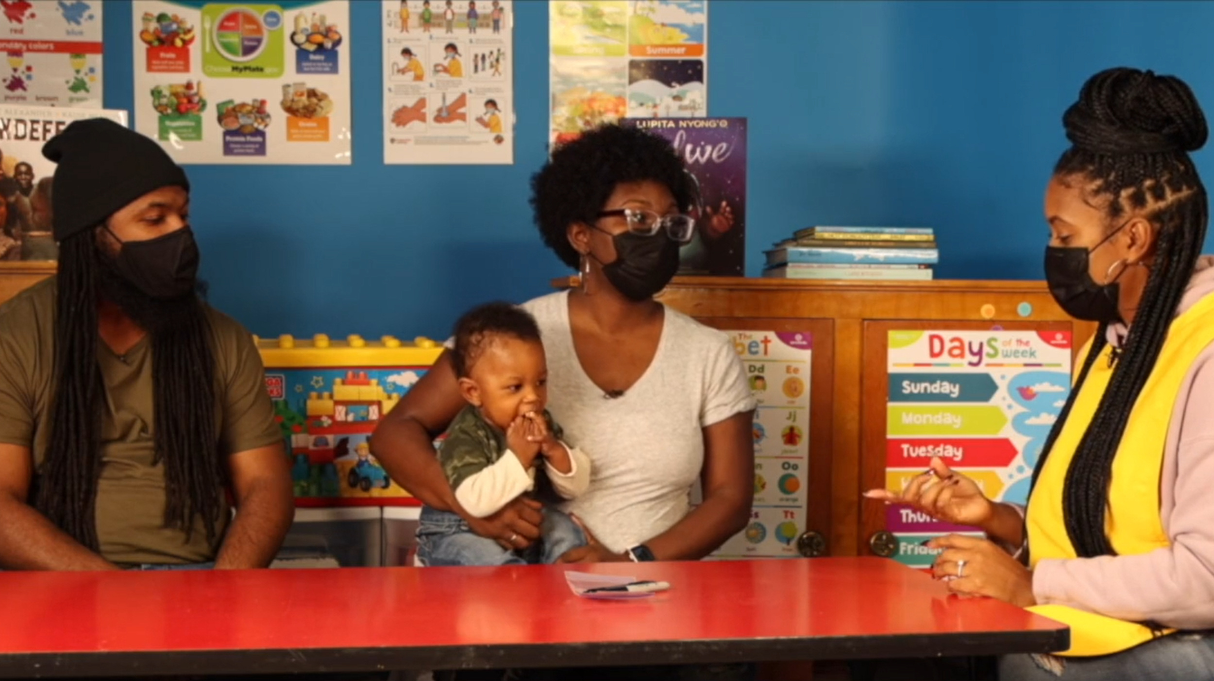 Three African american women with a young child talking together in a school room